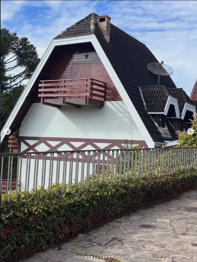 Fachada do chalé com telhado em A e sacada de madeira