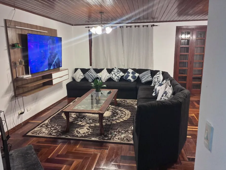 Sala de estar com sofá em L, TV e tapete